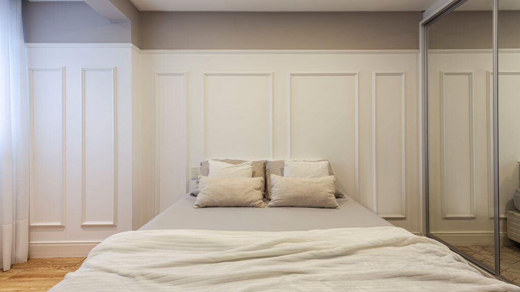 parede de quarto com boiserie aplicada como cabeceira da cama