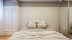 parede de quarto com boiserie aplicada como cabeceira da cama